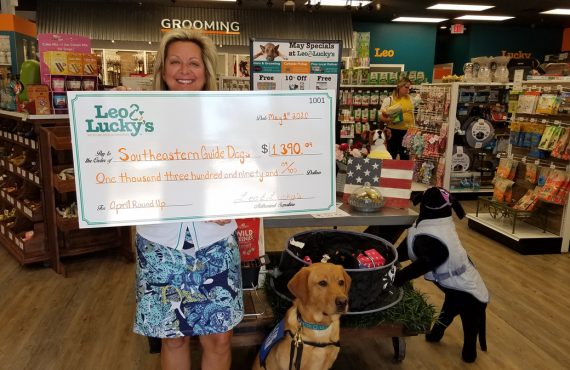 southeastern guide dogs rep with donation check from leo and luckys