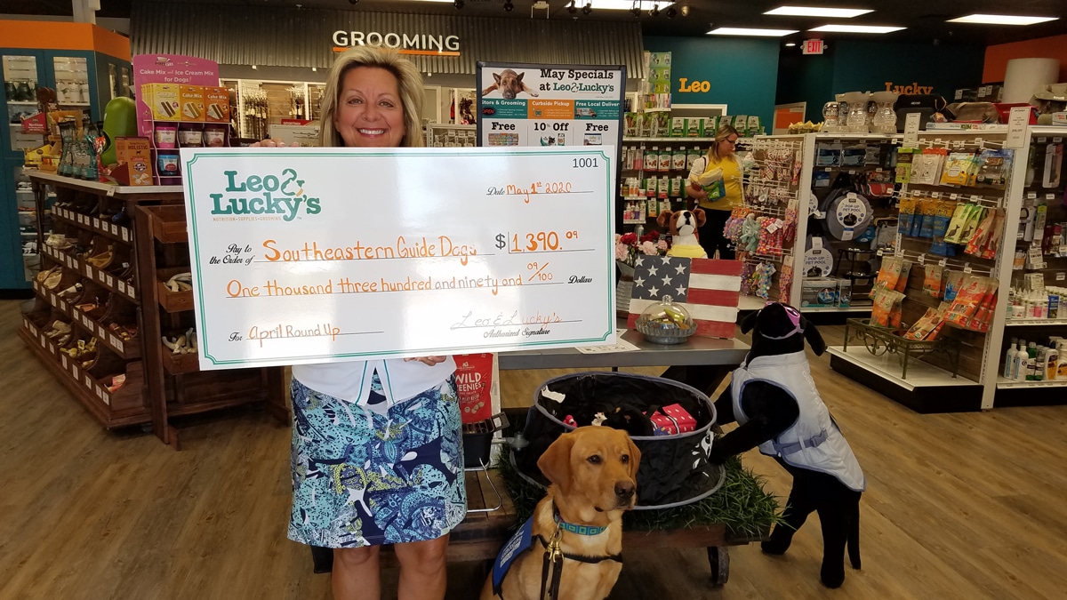 southeastern guide dogs rep with donation check from leo and luckys